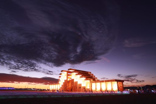 The illuminated structure of the 'Temple' at Burning Man 2019, photographed at dusk with dramatic clouds overhead. The long exposure capture
