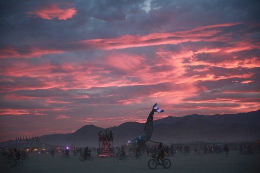 A dramatic sunset with pink and purple clouds over the Black Rock Desert during the 2016 Burning Man festival. A large whale sculpture with