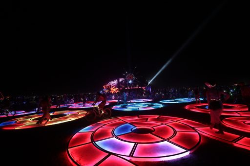 A wide-angle shot captures the "Temple" art installation at Burning Man 2017, featuring illuminated circular platforms on the playa at night