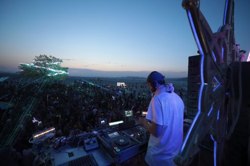 A DJ performs at dusk during the Burning Man festival in Lovelock, Nevada. The DJ booth is equipped with turntables and a mixer, set against