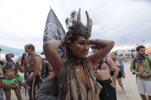 A woman with elaborate braided hair and a metallic crown adorned with horns poses for a portrait at Burning Man 2017 in Lovelock, Nevada. Sh