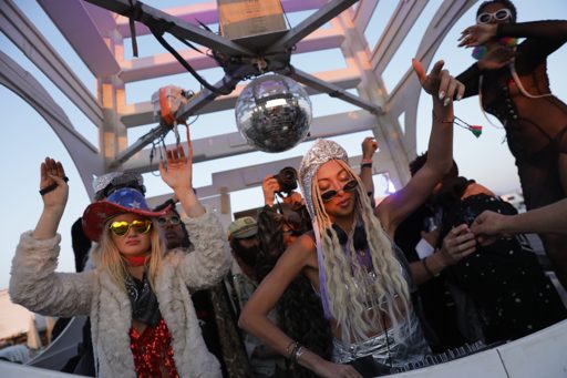 Two women dance under a disco ball and a pyramid structure at Burning Man, an annual event held in the Black Rock Desert, Nevada. The woman