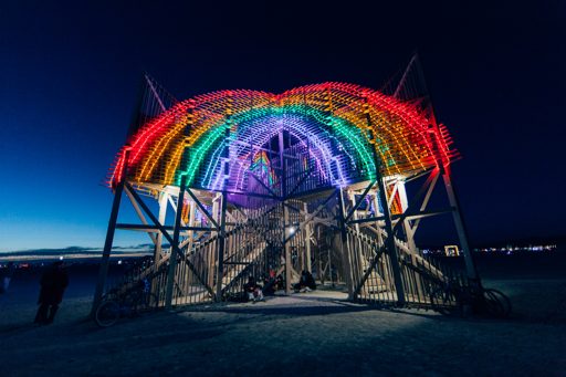 The "Cathedral of Mirrors" art installation, illuminated by a rainbow of LED lights, stands tall against the night sky at Burning Man 2015.