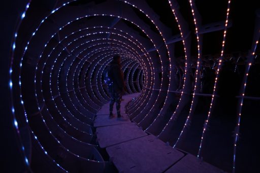 A person walks through a tunnel of illuminated rings and lights at the Burning Man festival in Lovelock, Nevada. The installation features c